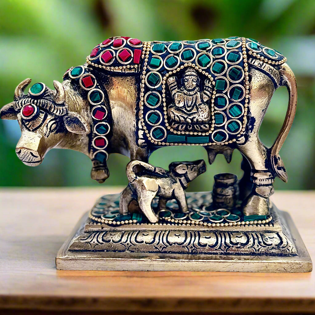 Decorative metal statue of a cow and calf with gemstone details on a white background